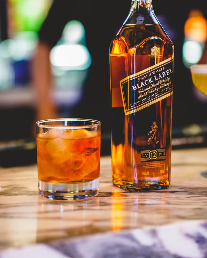 Whiskey pour beside a bottle of scotch